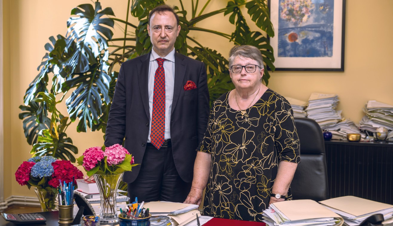 Dr. Helene Klaar und Dr. Norbert Marschall hinter Schreibtisch stehend im Büro der Dr. Norbert Marschall & Dr. Helene Klaar Kanzlei
